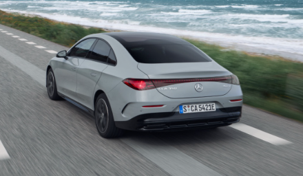 Mercedes CLA EV driving along a coastline showcasing sleek design and long-range styling